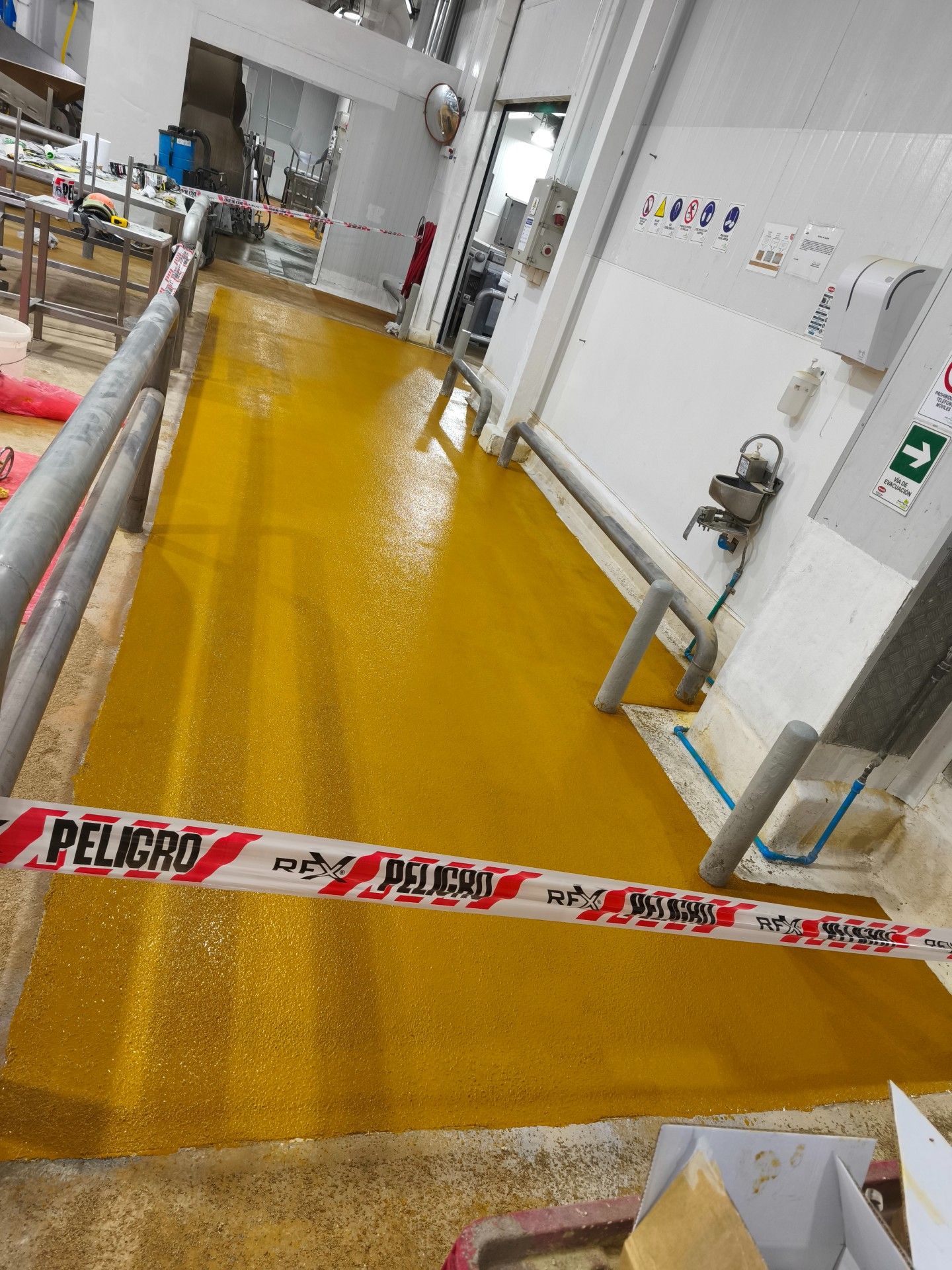 Revestimiento de piso amarillo en ejecución dentro de una planta, trabajo de MAKADI