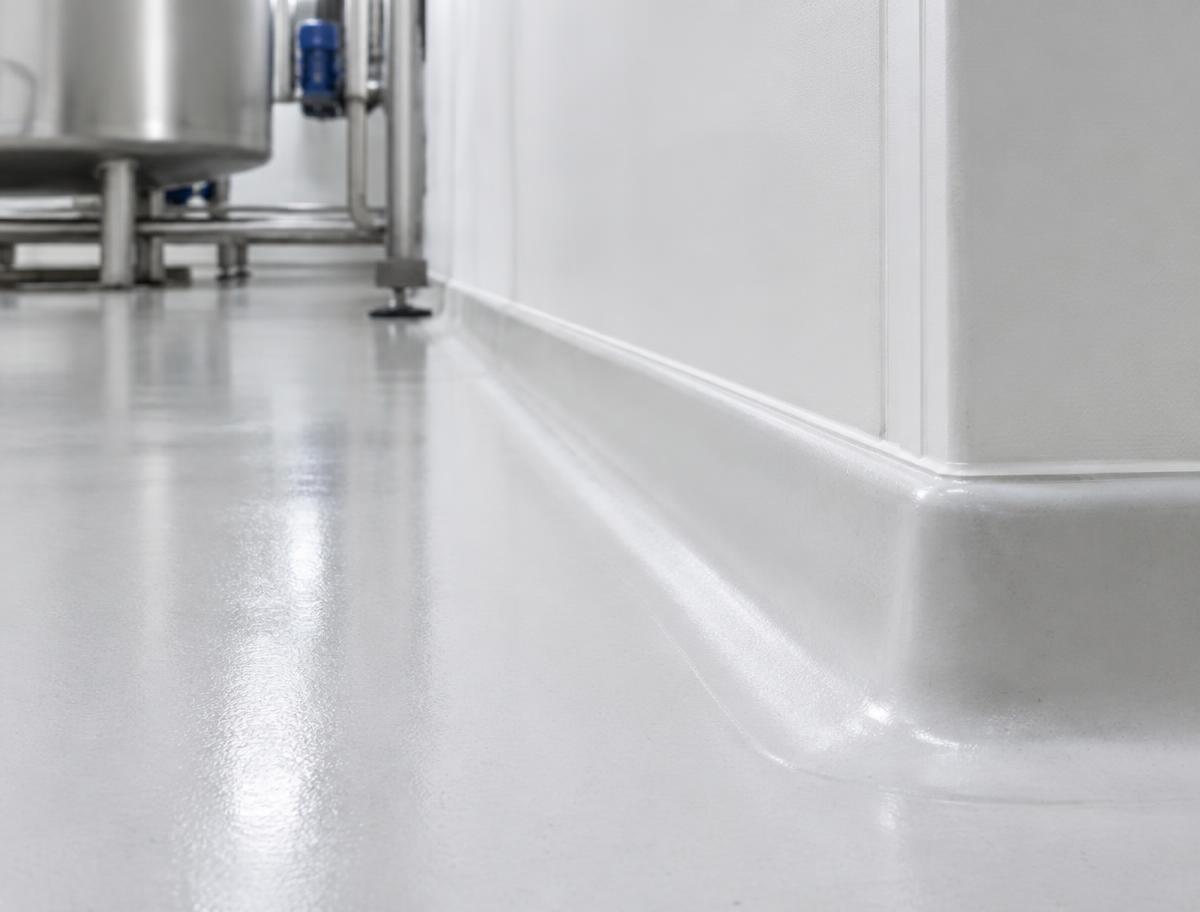 Rodón sanitario entre piso y muro en planta industrial, imagen ilustrativa